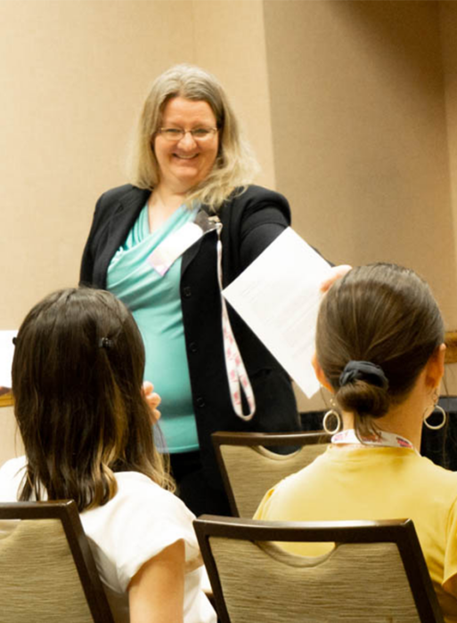 Tracy Costello during her talk at the 2020 Annual Life Science Women's Conference. She has blonde hair, is wearing a turqoise shirt and black blazer.