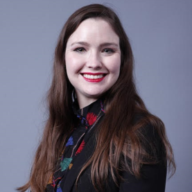 Stephanie smiles brightly, long brown hair cascading over a professional black blazer.